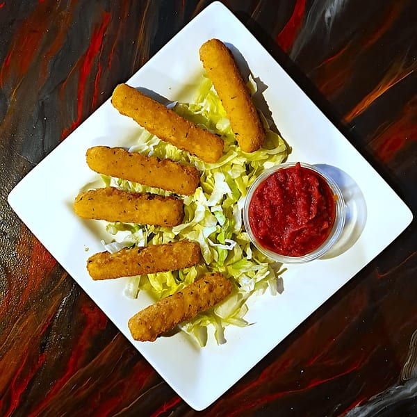 Golden-brown mozzarella sticks on a bed of shredded lettuce with a side of marinara sauce.