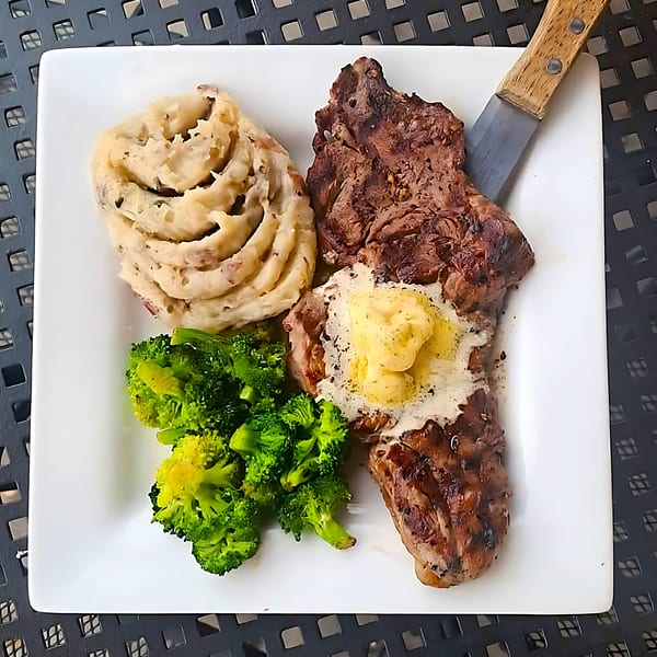 Broadway Grille's steak dinner with mashed potatoes, broccoli, and a knife on a white plate.