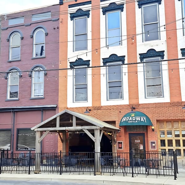 The Broadway Grille restaurant exterior with an outdoor patio under a wooden pergola.